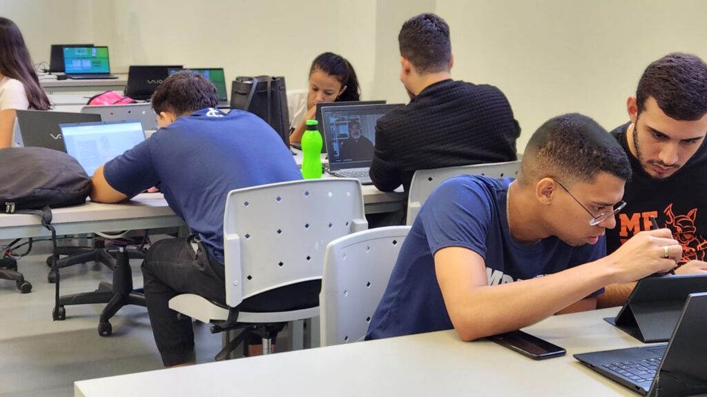 Alunos em sala de aula utilizando a plataforma Paciente 360, exemplificando o modelo de educação híbrida com discussões clínicas interativas.